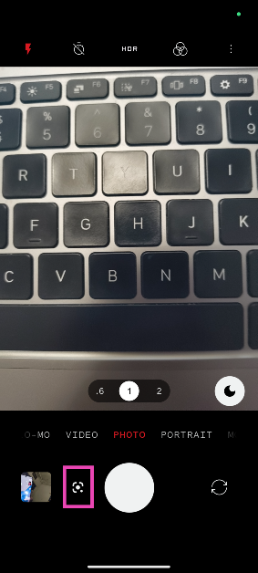 When the camera opens up, find the Google lens button next to the shutter button.